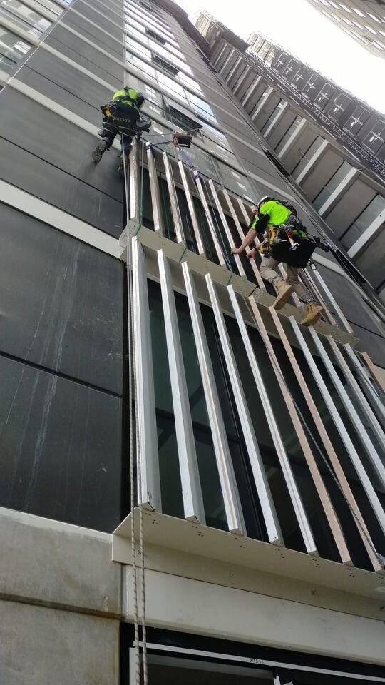 Rope access technician completing façade finishing works at Upper House South Brisbane