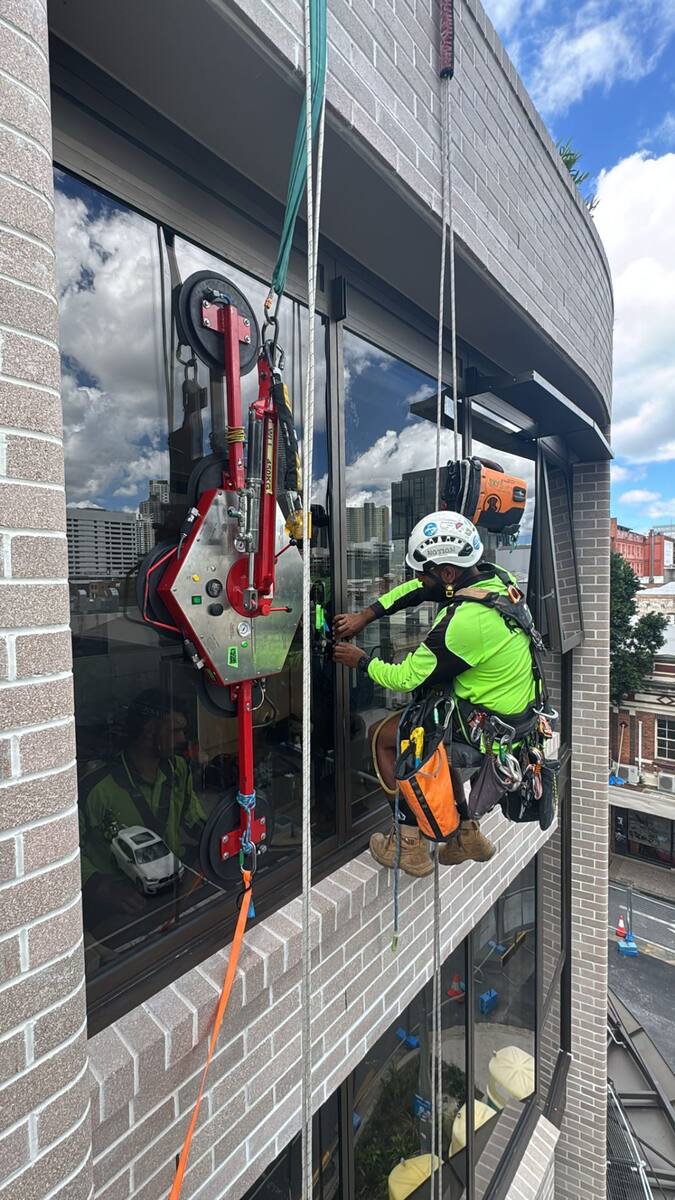 Trade qualified glazier performing high-rise glass replacement via rope access in Sydney