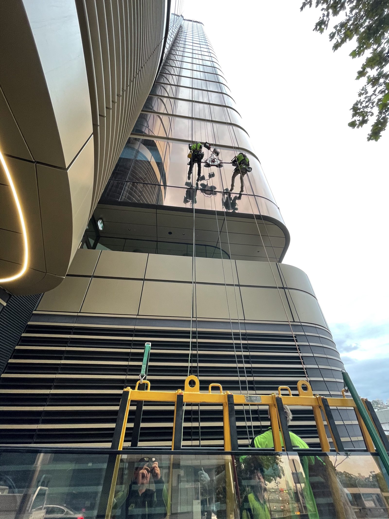 Two rope access technicians working on the curved glazed façade of Zurich Tower at 118 Mount Street North Sydney